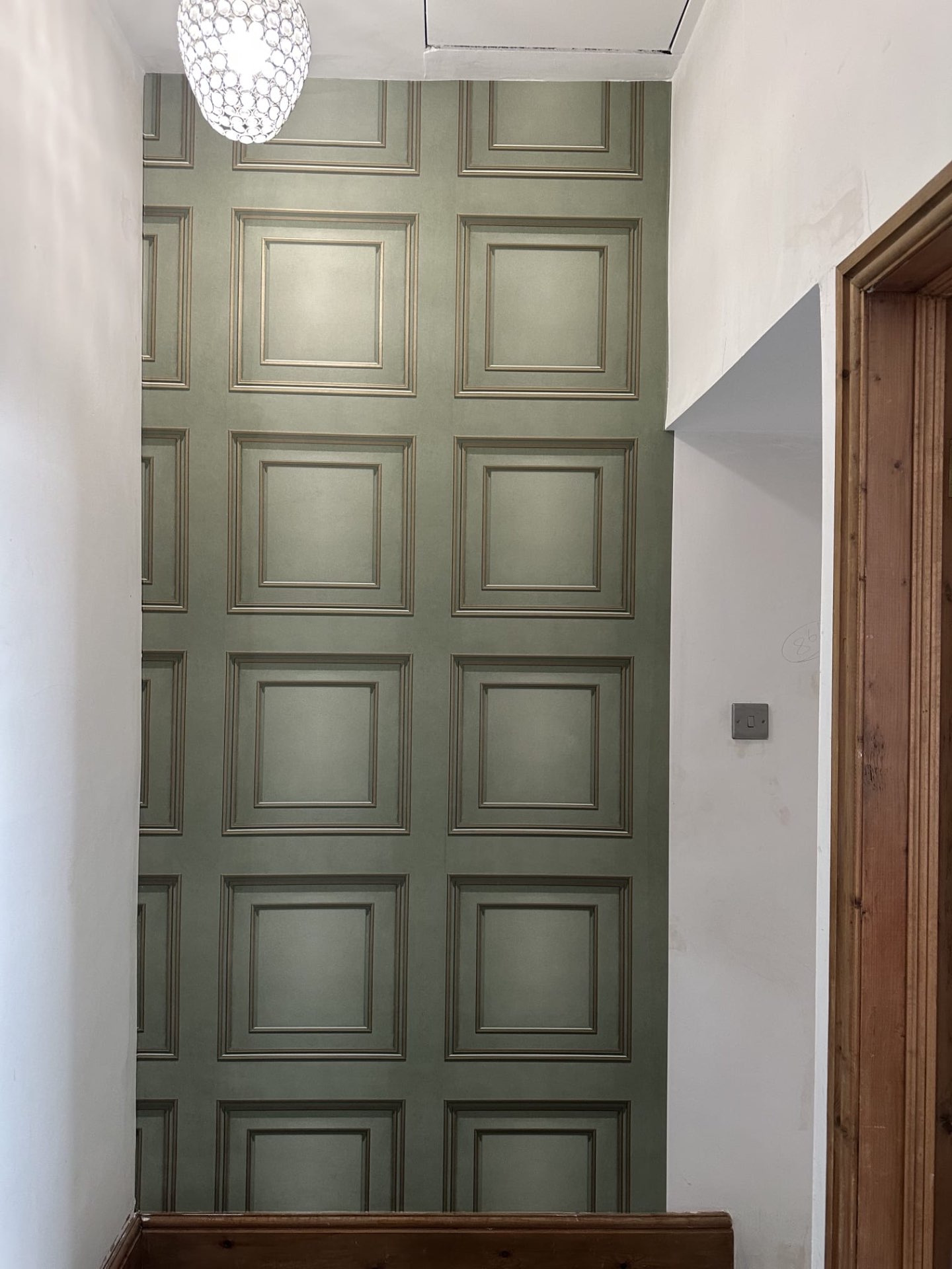 Sage green panelled wallpaper in a hallway