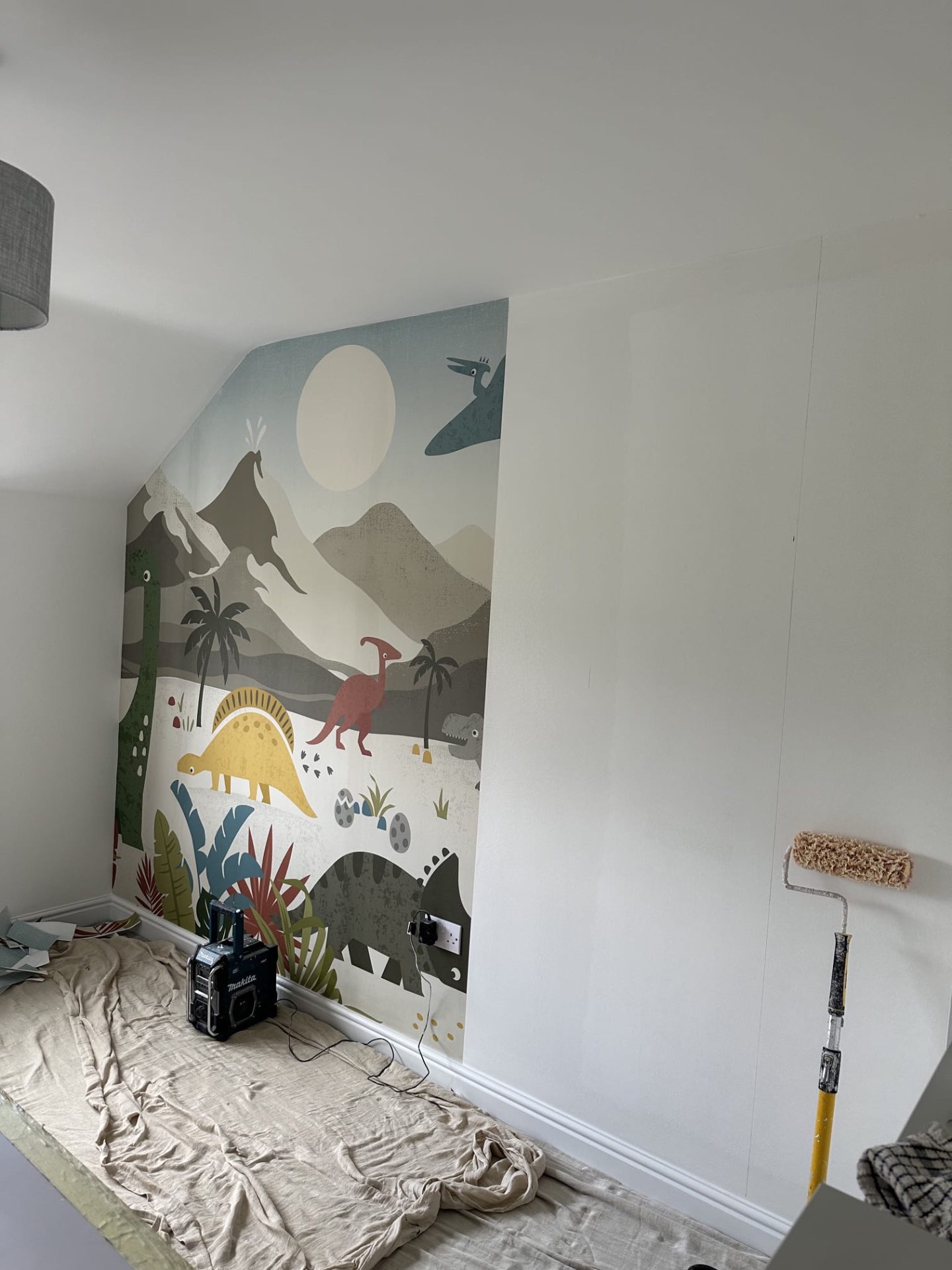 Dinosaur mural wallpaper going up in a child's bedroom